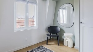 Ein Zimmer mit Fenster, Stuhl, Toilette und Spiegel.