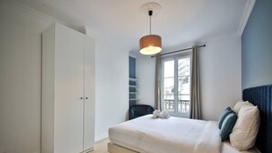 Ein Schlafzimmer mit Bett, Kleiderschrank, Fenster mit Blick und einer Pendelleuchte.