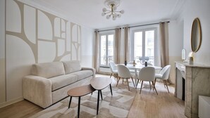Ein modernes Wohnzimmer mit Sofa, Couchtisch, Esstisch mit Stühlen, Kamin und großen Fenstern.