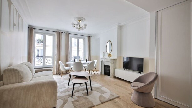 Ein modernes Wohnzimmer mit einer Couch, einem Esstisch mit Stühlen, einem Fernseher und einem Kamin.