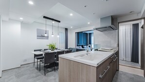 A modern kitchen with a central island, a dining area with chairs, and a view of the city through the window.