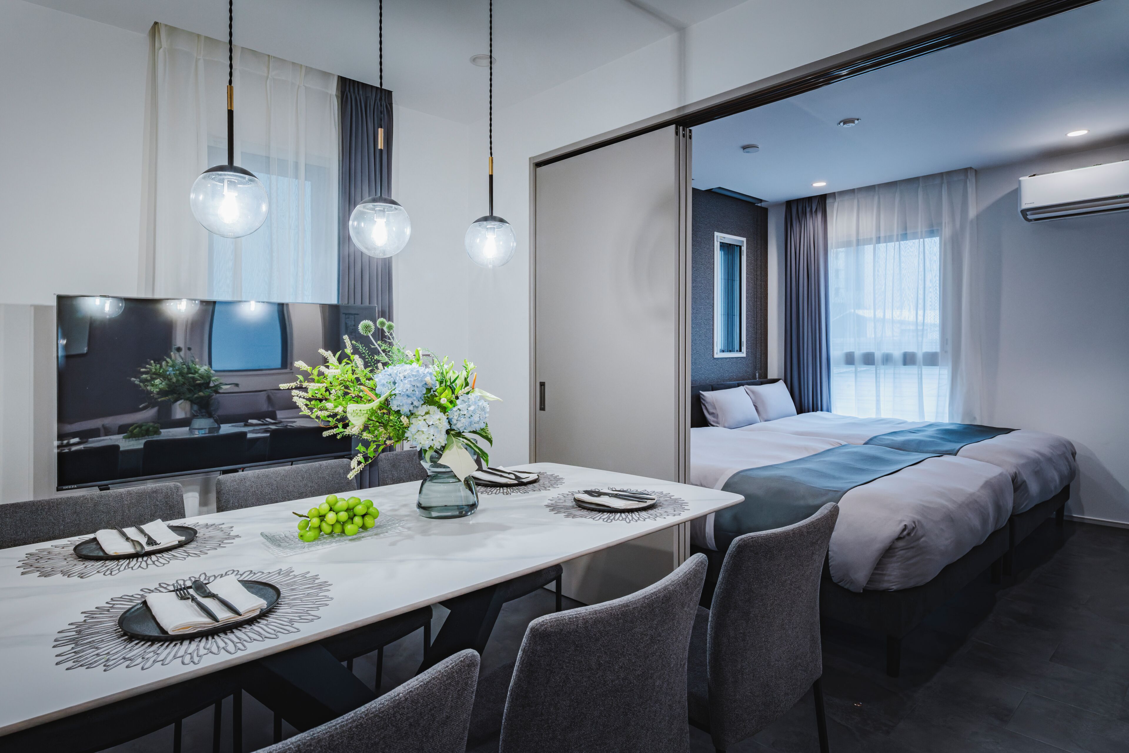 Una habitación de hotel moderna con comedor, cama y televisión.
