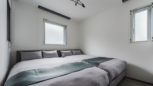 A bedroom with a bed, a window, and a ceiling light fixture.