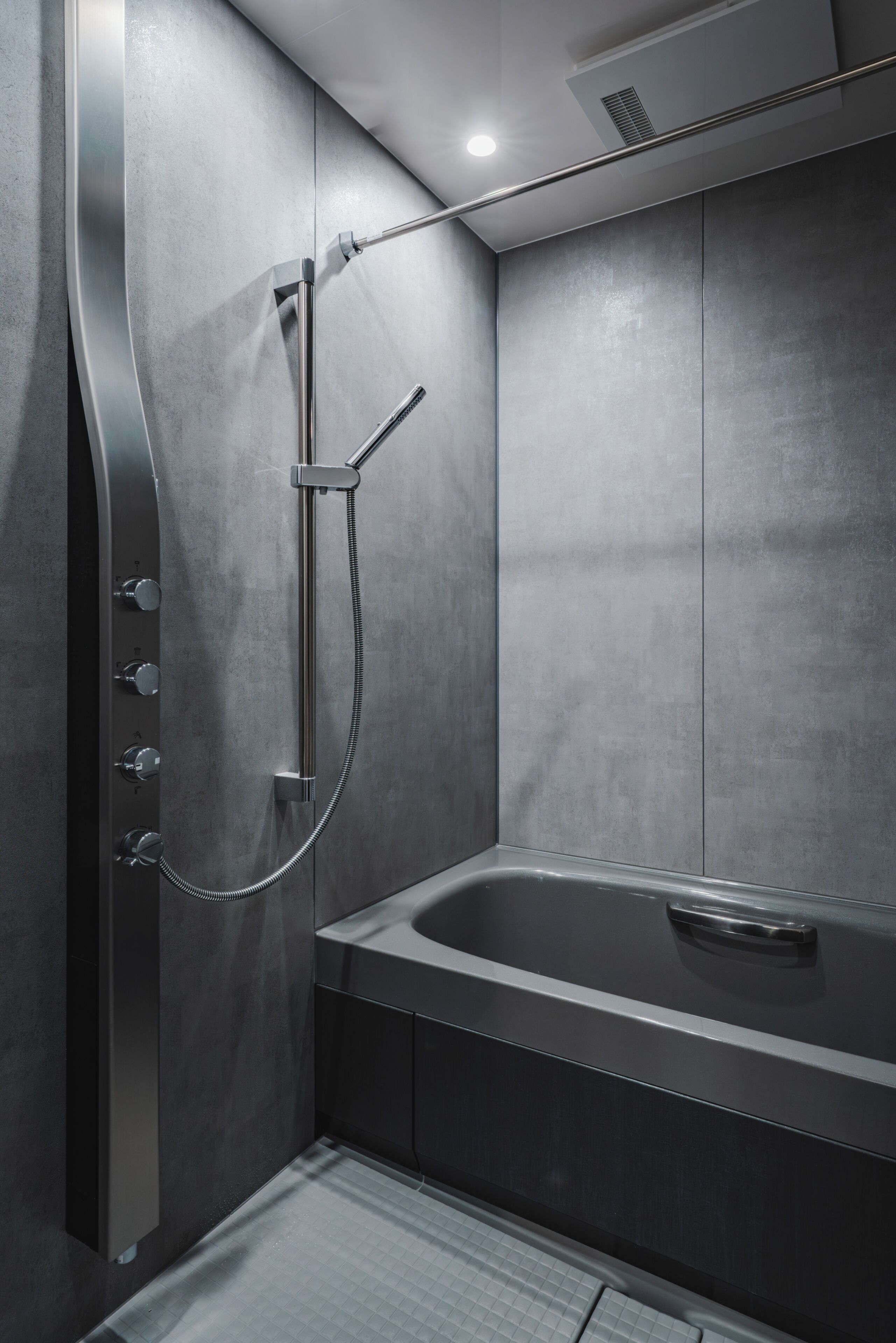 A modern bathroom with a shower, a bathtub, and a control panel.