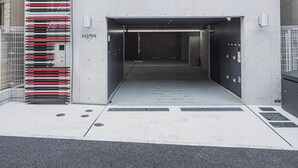 Un bâtiment moderne à la façade ornée de bandes verticales, doté d’une entrée de garage et d’une grille de sécurité.