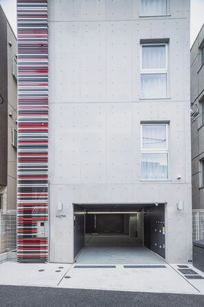 A modern building with a vertical striped facade, a garage entrance, and a security gate.