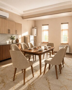 Una cocina moderna con comedor, que cuenta con encimera de mármol, armarios de madera y una mesa grande con sillas.