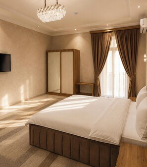 A bedroom with a large bed, a wardrobe, a television, and a chandelier.