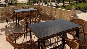 Un espacio al aire libre con mesas y sillas, con vistas a un jardín ajardinado y edificios al fondo.