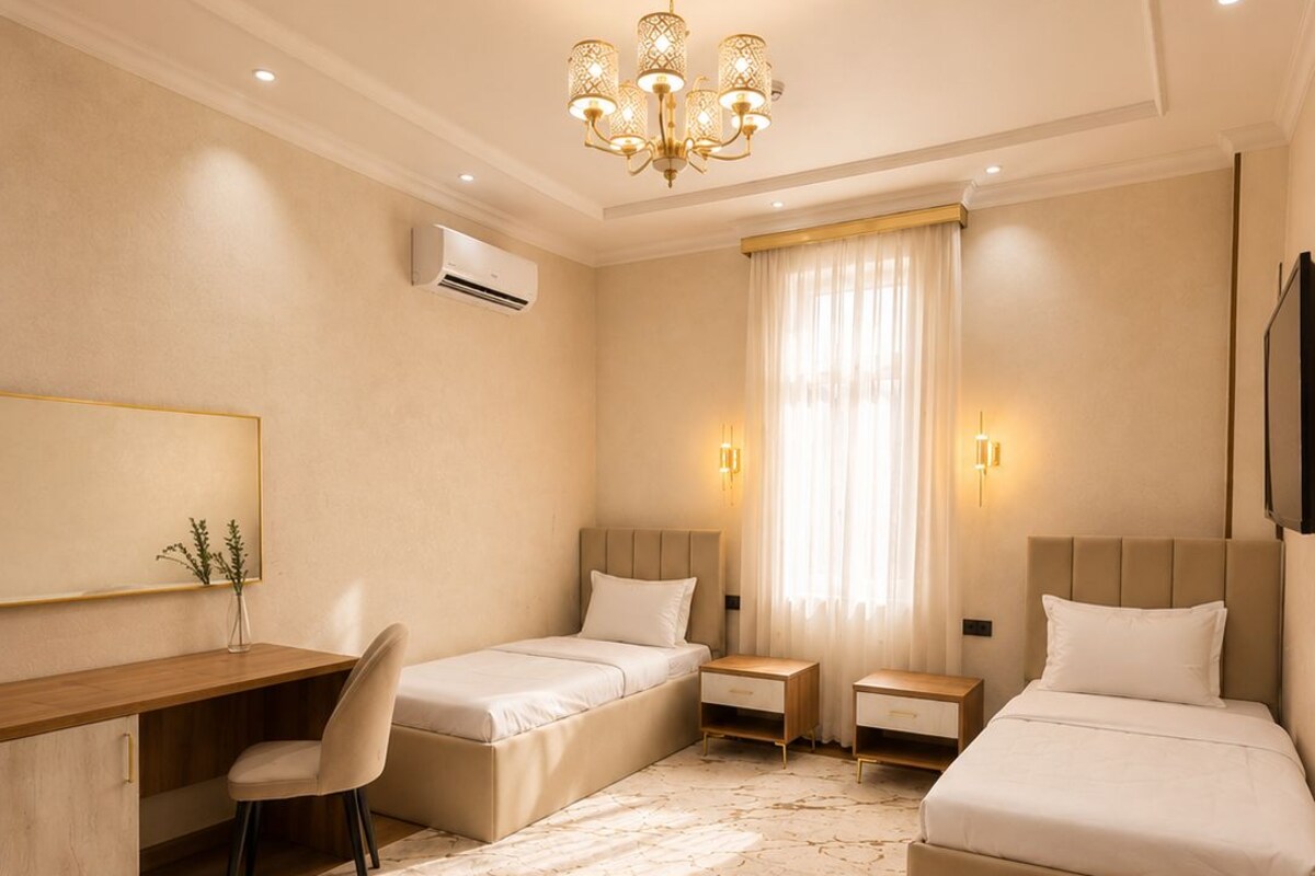 Una habitación de hotel con cama, escritorio, silla, televisor y candelabro.