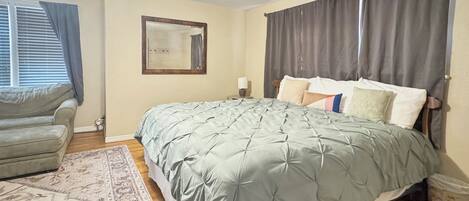 A bedroom with a bed, a ceiling fan, a window with blinds, a rug, and a nightstand.