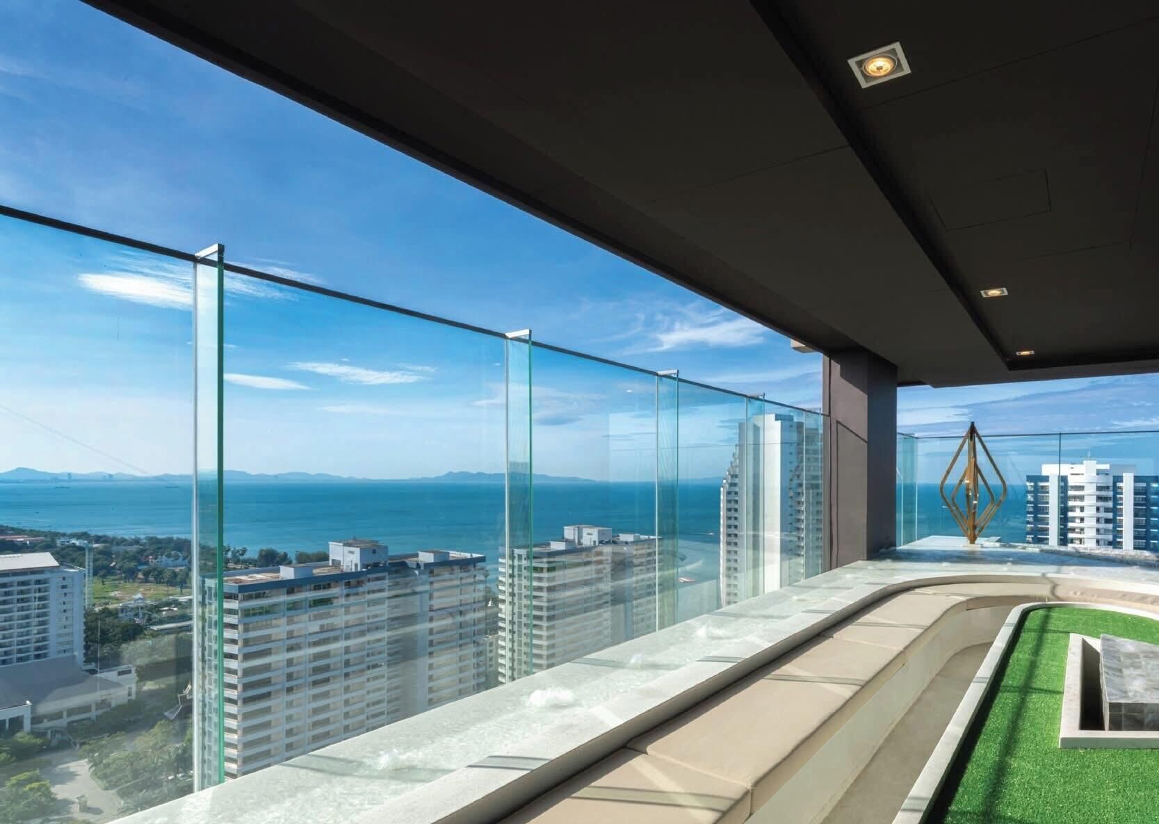 Un immeuble de grande hauteur doté d’un balcon en verre qui offre une vue sur le paysage urbain et une étendue d’eau.