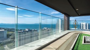 Un edificio de gran altura con balcón de cristal que ofrece vistas a un paisaje urbano y una masa de agua.
