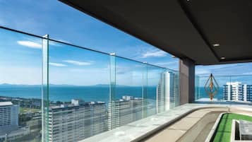 Un immeuble de grande hauteur doté d’un balcon en verre qui offre une vue sur le paysage urbain et une étendue d’eau.