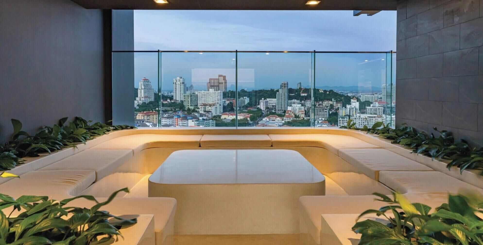 Eine moderne Lounge mit Stadtblick, inklusive einer gebogenen Sitzecke und Topfpflanzen.