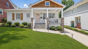 A two-story house with a front porch, stone pillars, and a well-maintained lawn.