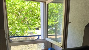 Quarto com escrivaninha, cadeira e janela com vista para o verde lá fora.