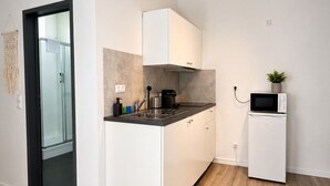 A modern kitchen with white cabinetry, a built-in microwave, and a small refrigerator. - MIILOX Apartments Chemnitz Rosenhof (Chemnitz)