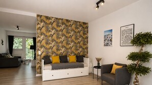 A modern living room with a sofa, a coffee table, and a potted plant. - MIILOX Apartments Chemnitz Rosenhof (Chemnitz)