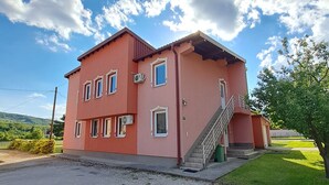 Un edificio de dos plantas con fachada roja, múltiples ventanas y una escalera que lleva a la entrada.