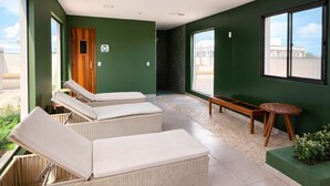 Una habitación moderna con una pared verde, un banco de madera y una pequeña mesa.