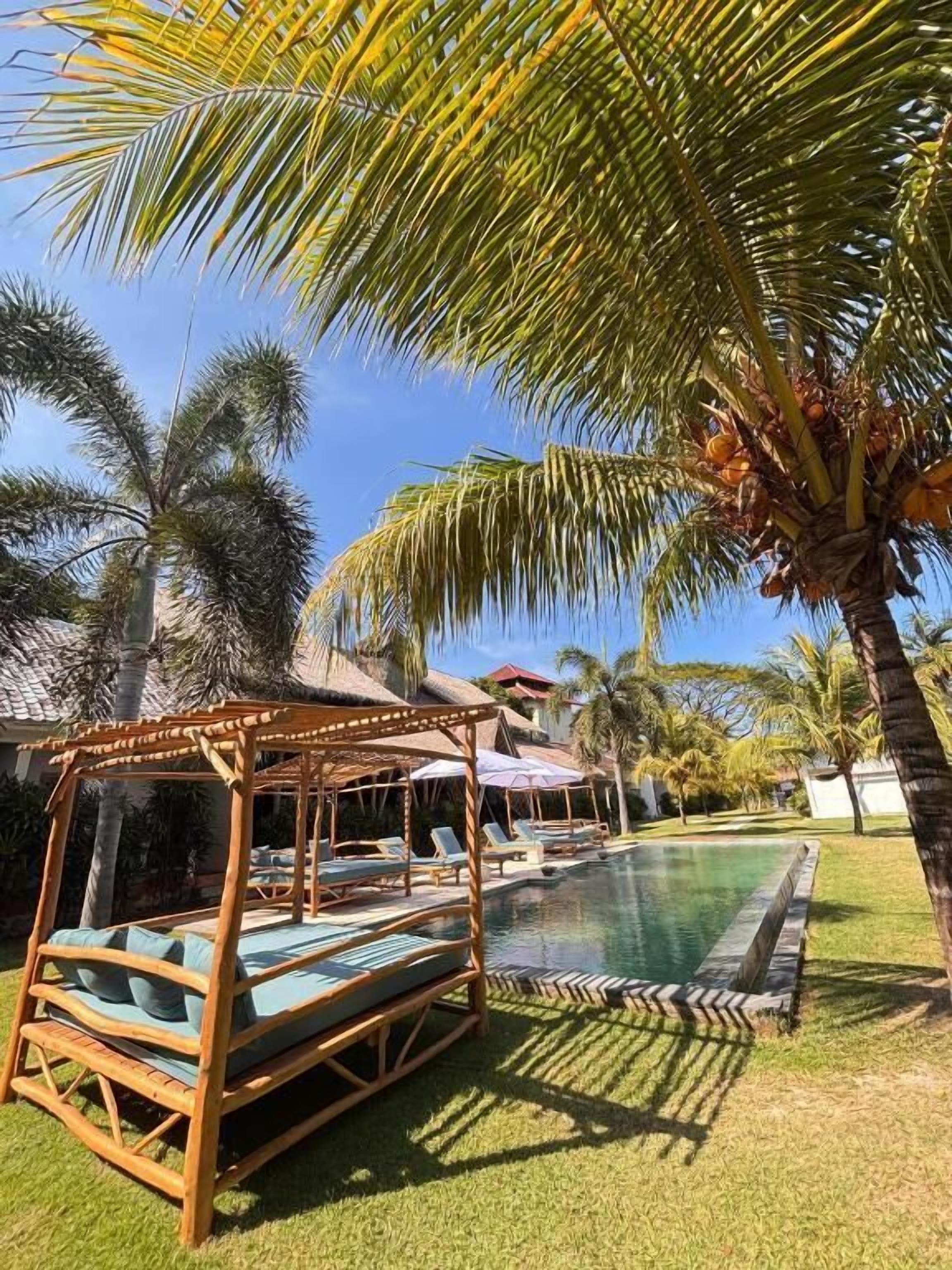 A pool area with lounge chairs and a wooden structure.