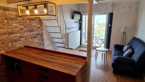 Eine Küche mit Holzarbeitsplatte, Ziegelwand, Treppe, Fernseher und einem Balkon mit Tisch und Stühlen.