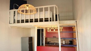 Ein kleines Zimmer mit Etagenbett, Küchenzeile und Essbereich.