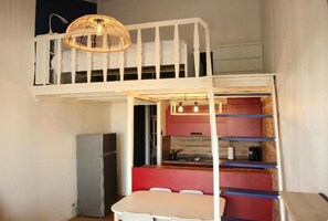 Ein kleines Zimmer mit Etagenbett, Küchenzeile und Essbereich.
