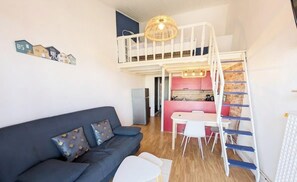 Un espacio habitable compacto con sofá, mesa de comedor y kitchenette.