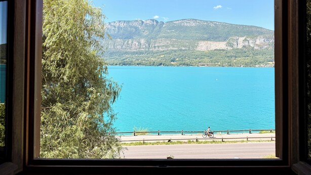 A view through a window of a lake with mountains in the background. - Calimas House on the shores of Lake Annecy (Talloires-Montmin)