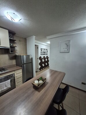 Una cocina moderna con horno empotrado, refrigerador y una mesa de comedor con sillas.