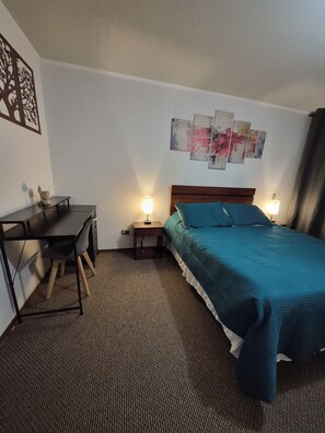 A hotel room with a bed, a desk, and two bedside lamps. - Cozy Apartment with a Balcony, Pool, and Beautiful View in Valparaíso (Valparaíso)