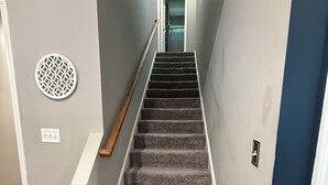 A carpeted staircase with a handrail, a circular wall decoration, and a black object on the floor. - Spacious 3BR/3BA Home Patio, Yard & Garage (Kathleen)