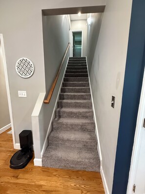 A carpeted staircase with a handrail, a circular wall decoration, and a black object on the floor. - Spacious 3BR/3BA Home Patio, Yard & Garage (Kathleen)