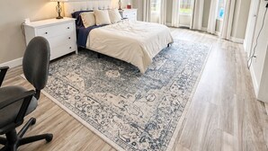 A bedroom with a bed, desk, chair, ceiling fan, and a large window with curtains. - Spacious 3BR/3BA Home Patio, Yard & Garage (Kathleen)