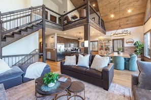 A spacious living area with a high ceiling, a staircase, a dining area, and a kitchen. - Family Retreat w/ Indoor Pool - Sleeps 20 (Sevierville)