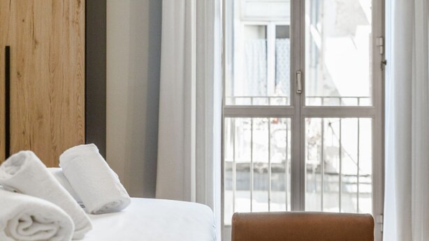 Ett hotellrum med en säng, en väggpanel av trä, ett fönster med utsikt och en stol.
