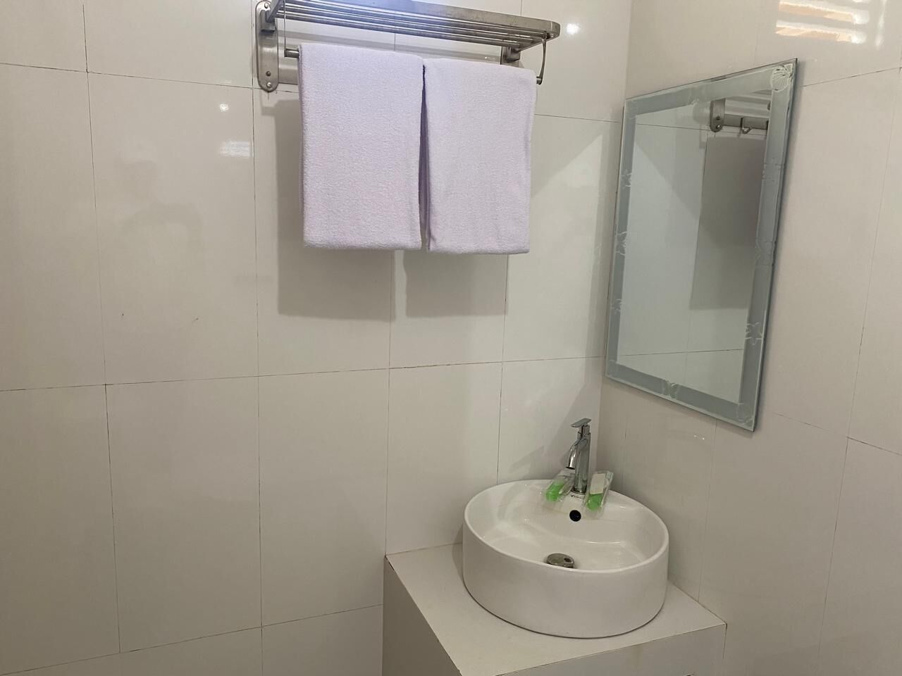 Une salle de bain avec un lavabo blanc, un miroir et un porte-serviettes.