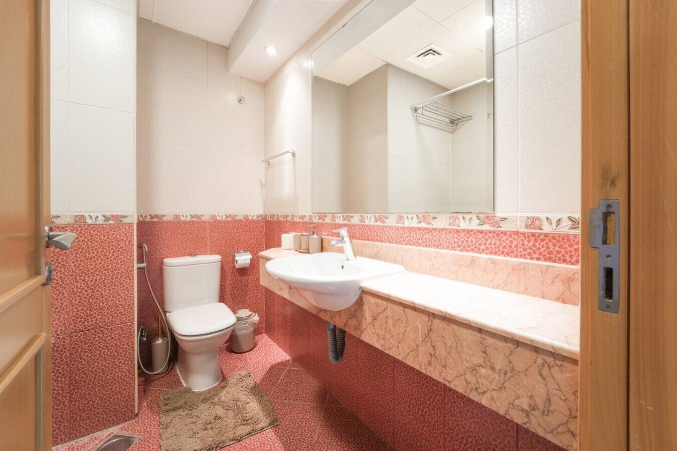 Et badeværelse med toilet, vask og bruser.