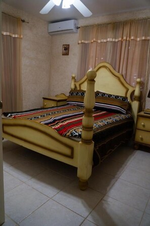 Ein Schlafzimmer mit einem hölzernen Bett, einem Nachttisch, einer Kommode und einem Deckenventilator.