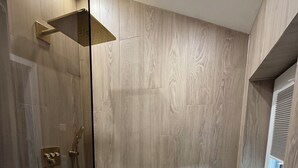 A modern bathroom with a shower, a vanity with a mirror, and a window.