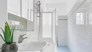 Un bagno moderno con una vasca da bagno bianca e spaziosa, un box doccia in vetro e una pianta in vaso.