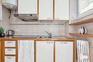Eine Küche mit weißen Schränken, einer Edelstahl-Dunstabzugshaube, einem Spülbecken und einem Heizkörper an der Wand.