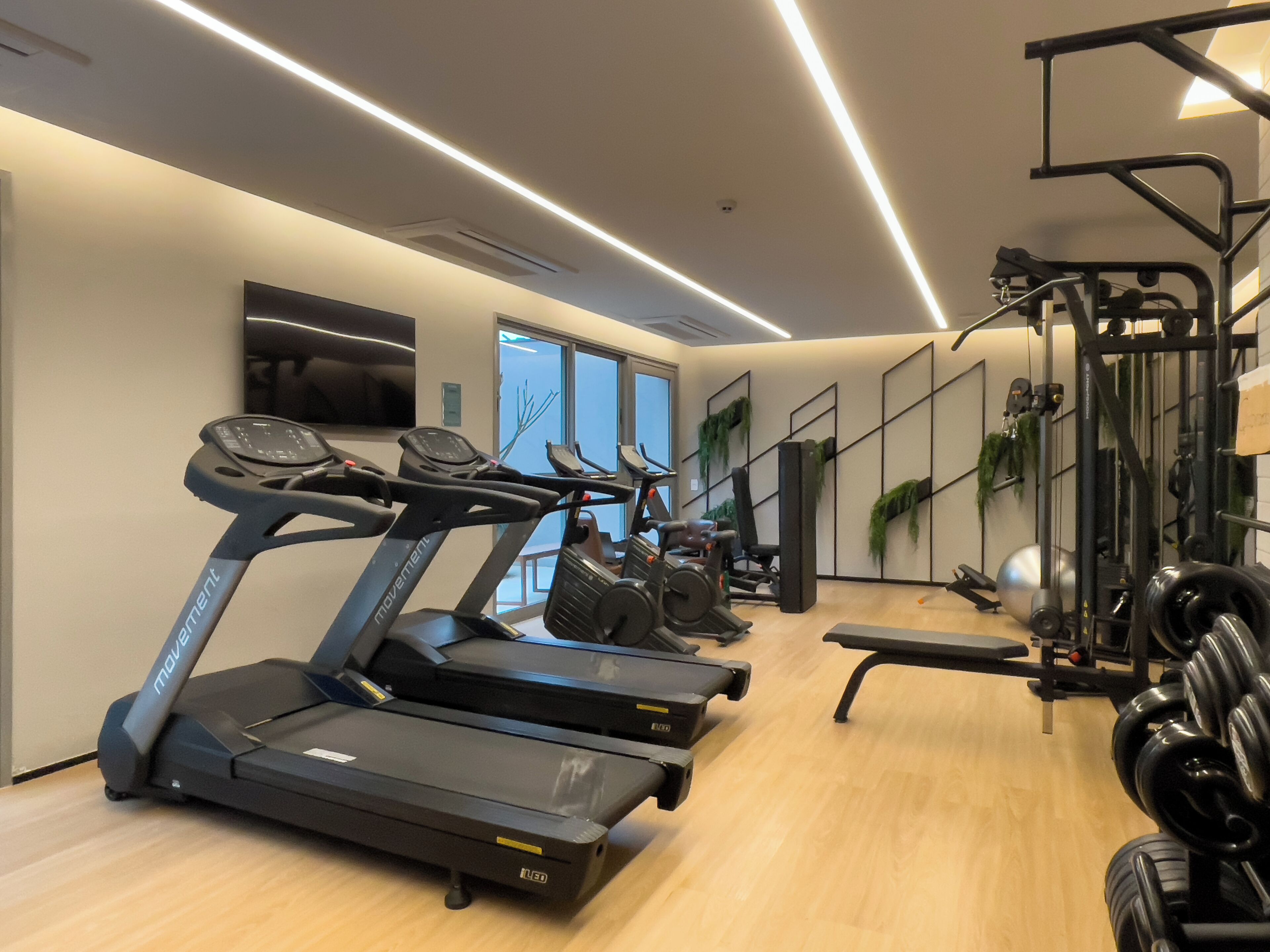 Ein Fitnessraum mit Laufbändern, Krafttrainingsgeräten und einem Spiegel.