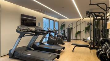 Une salle de sport équipée de tapis de course, d’appareils de musculation et d’un miroir.