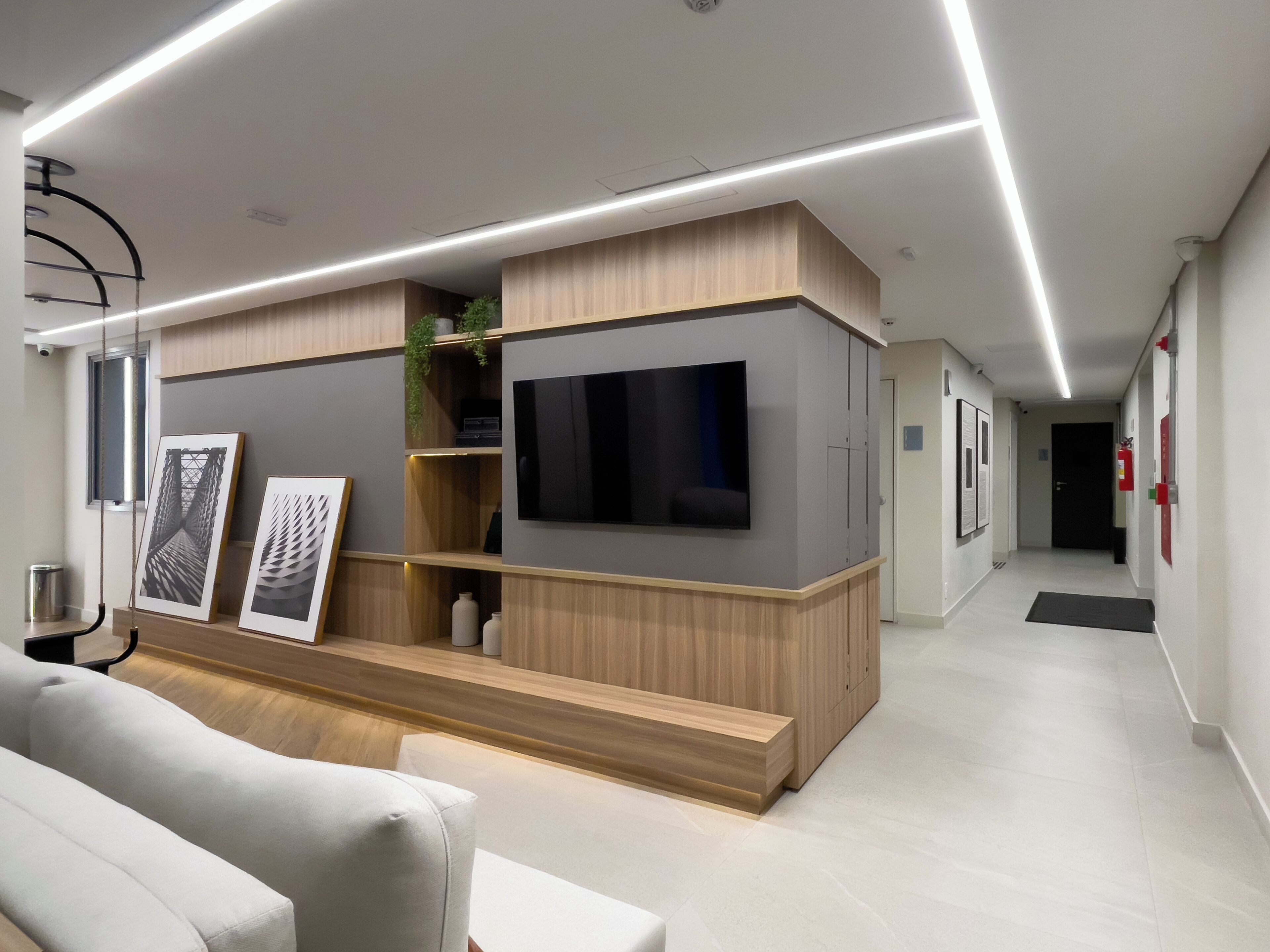 Una sala moderna con televisor de pantalla plana, estanterías de madera y un sofá.