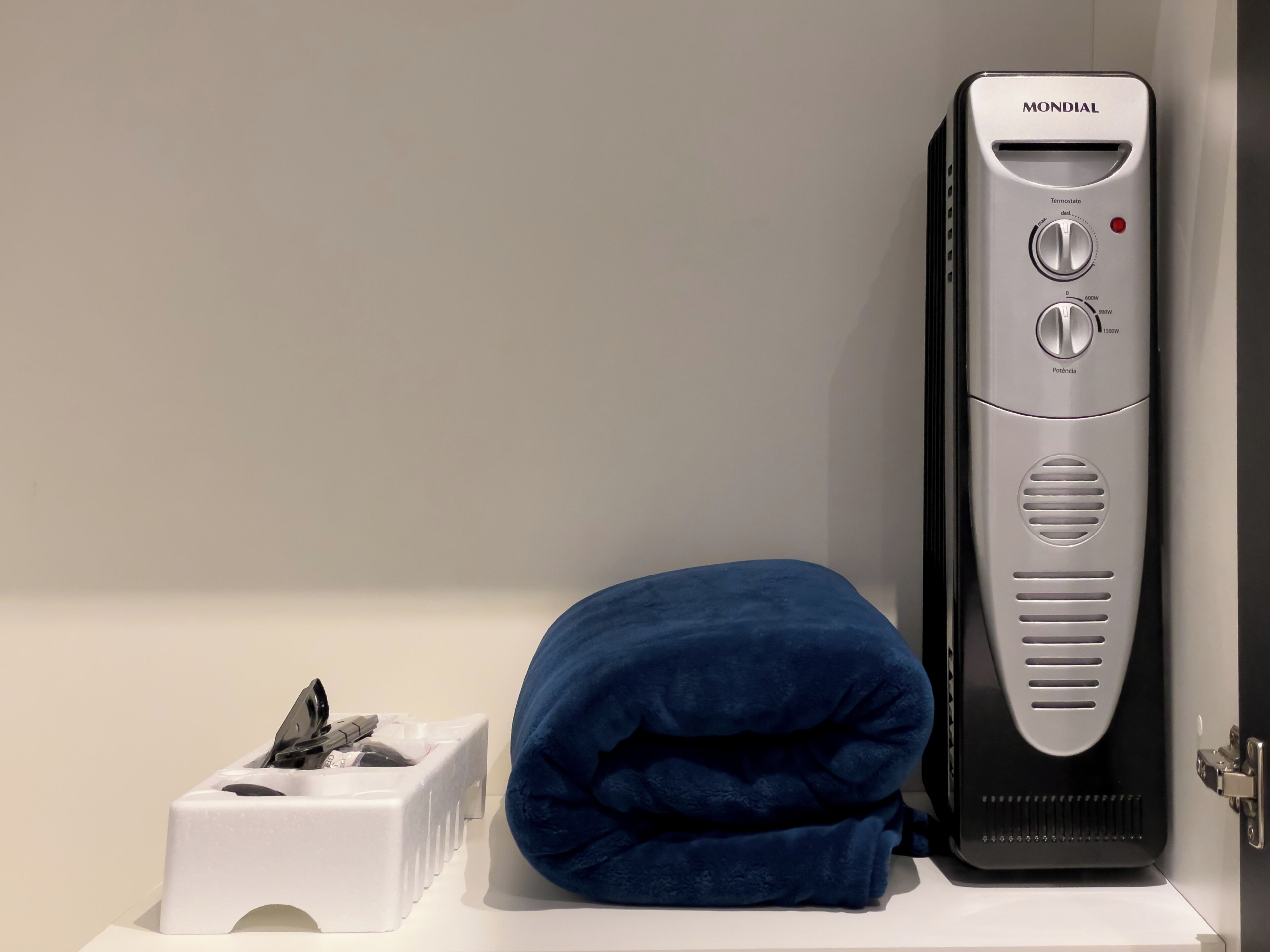 A bathroom with a white sink, a blue towel, and a black and silver electric shaver.