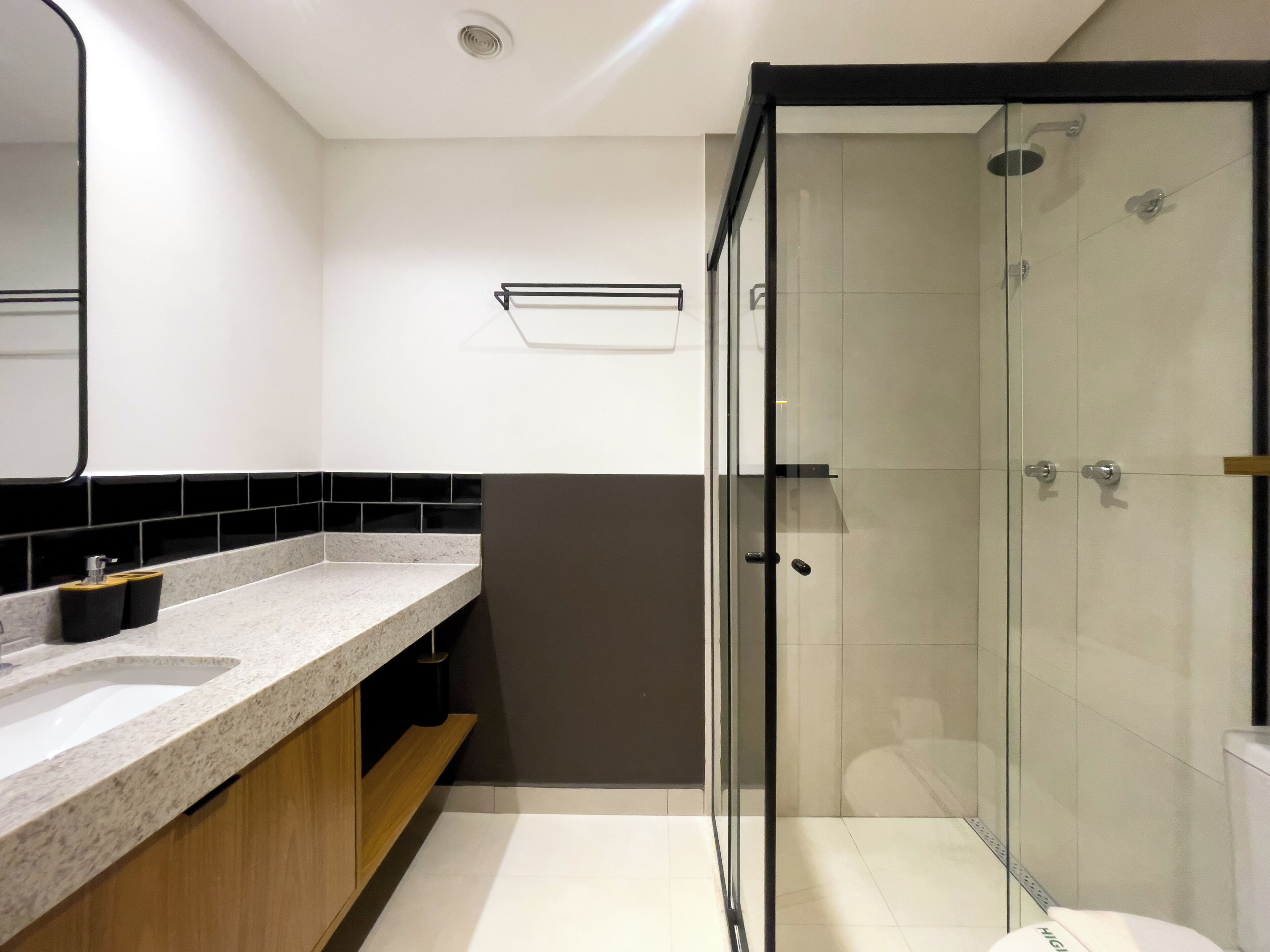 A modern bathroom with a glass shower enclosure, a sink with a marble countertop, and a mirror above the sink.