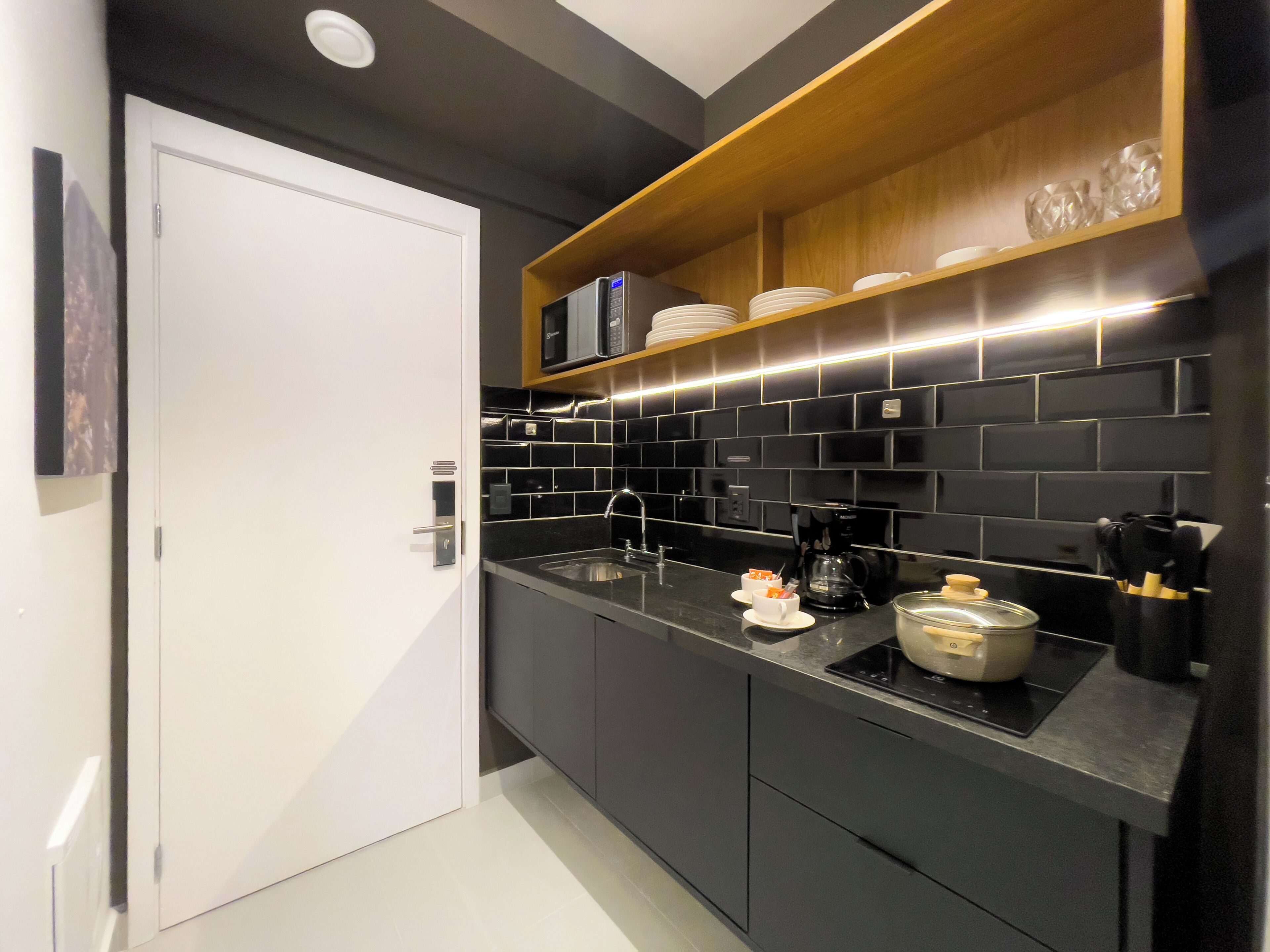 A modern kitchen with black tiles, a coffee maker, and a microwave on the countertop.